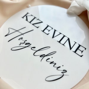 May include: White round sign with black text that reads "KIZ EVINE Hosgeldiniz".