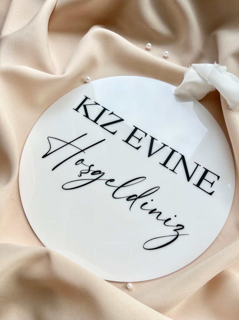 May include: White round sign with black text that reads "KIZ EVINE Hosgeldiniz".