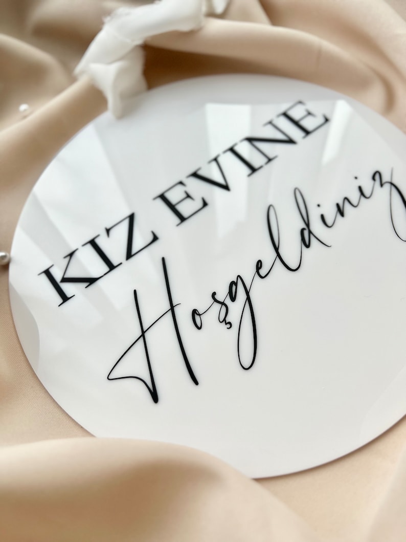 May include: White round sign with black text that reads "KIZ EVINE HOSGELDINIZ".