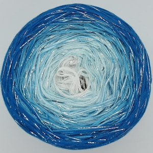 Può includere: Un gomitolo di filato blu e bianco ombré con filo argentato.