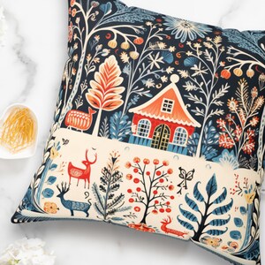 May include: Square cushion featuring a forest design with a red house, deer, and plants in blue, orange, and cream against a dark blue backdrop. The cushion is square in shape and suitable for home decor.