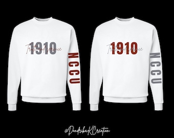 Può includere: Due felpe bianche con la scritta "1910 Truth and Service" in grigio e bordeaux. Le maniche presentano le lettere "NCCU" in bordeaux e grigio. Le felpe sono esposte su sfondo nero.