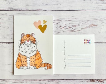 May include: A postcard featuring a cartoon orange cat with closed eyes and a happy expression. The cat is surrounded by three hearts, two pink and one gold. The postcard is white with a blank space for writing a message on the back. The back of the postcard has the text "KAYNI PAPER" printed in rainbow colors.