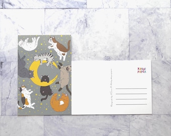 May include: A postcard featuring a gray background with various cartoon cats in different poses, including one on a crescent moon. The postcard also has a blank white side with lines for an address and the text "KAYNI PAPER".