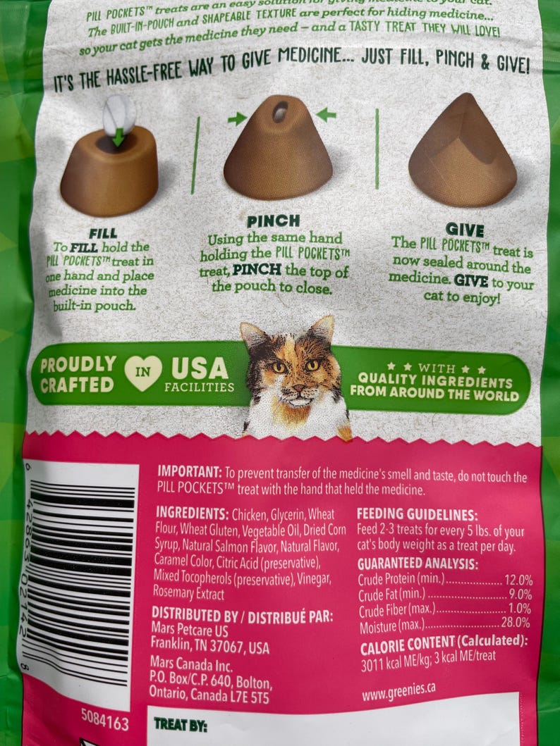 May include: Green bag of cat treats, Pill Pockets, with instructions: Fill, Pinch, and Give. The bag features a cat illustration and text about the product's features and ingredients. The treats are designed to help cats take medicine.