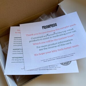 May include: A cardboard box containing a sampler pack of cat medication products. The pack includes a card with the text "MeowMeds" and information about the products. The card also includes the text "We hope your kitty feels better soon."