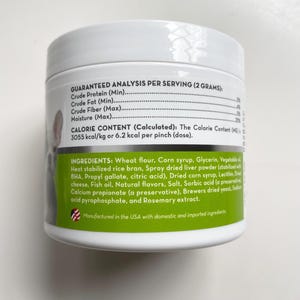 May include: A white pet food container with a green label. The label lists ingredients, including wheat flour, corn syrup, and dried liver powder. The container also displays a nutritional analysis per serving.
