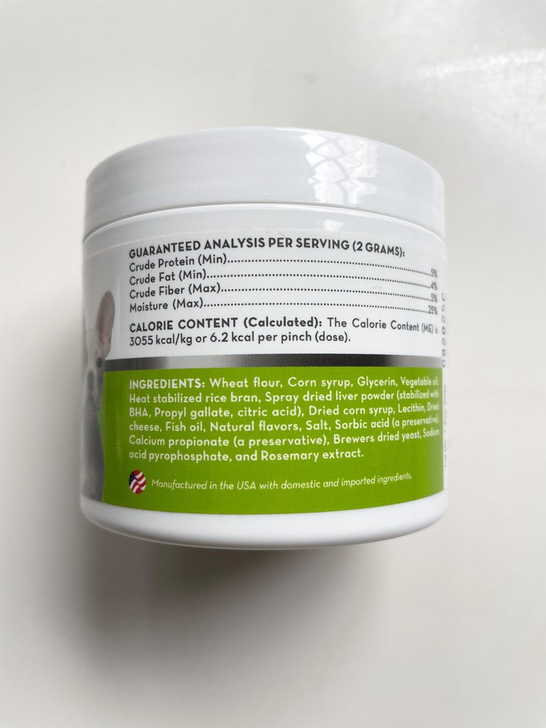 May include: A white pet food container with a green label. The label lists ingredients, including wheat flour, corn syrup, and dried liver powder. The container also displays a nutritional analysis per serving.