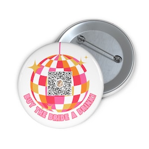 Puede incluir: Un botón blanco con una bola de discoteca rosa y naranja con un código QR en el centro. El texto "BUY THE BRIDE A DRINK!" está escrito alrededor de la bola de discoteca.
