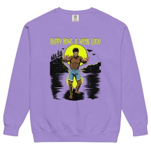 May include: A light purple long-sleeve sweatshirt featuring a graphic print of a werewolf standing in water against a yellow moon. The text "HAPPY HOWL-O-WEEN, LOCAL!" is printed in yellow above the illustration, which includes trees and bats.