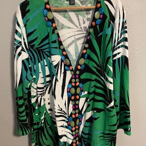 Könnte beinhalten: Eine weiße Keramik-Tasse mit schwarzem Henkel und dem Text "But First, Coffee" in handschriftlichem Stil. Die Tasse steht auf einer weißen Oberfläche. Die Tasse ist etwa 10 cm hoch.