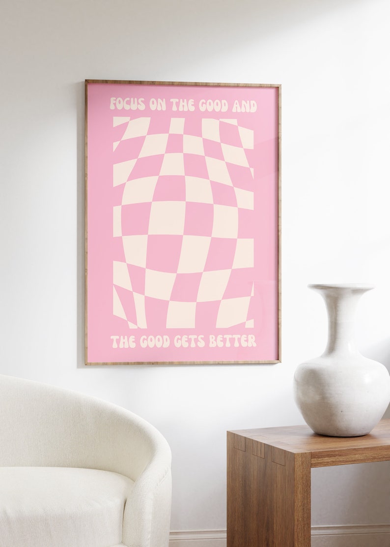 May include: A pink and white checkered poster with the text "Focus on the good and the good gets better" in a retro font.