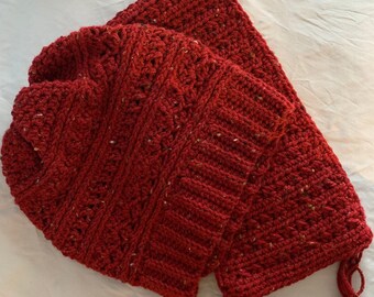 May include: A red crocheted hat and scarf set with a textured pattern. The scarf has a fringe at the end.