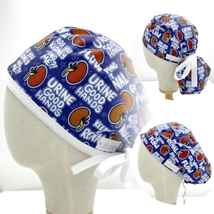May include: A blue surgical scrub cap with a white trim and ties. The cap features a repeating pattern of cartoon kidneys, text that reads "Urine Good Hands," and other medical-themed phrases.