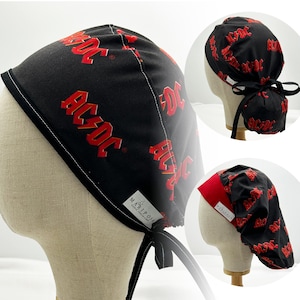 May include: Black and red surgical scrub hat with a repeating pattern of the AC/DC logo. The hat has a red band and a tie at the back. The hat is made by Mariposa.