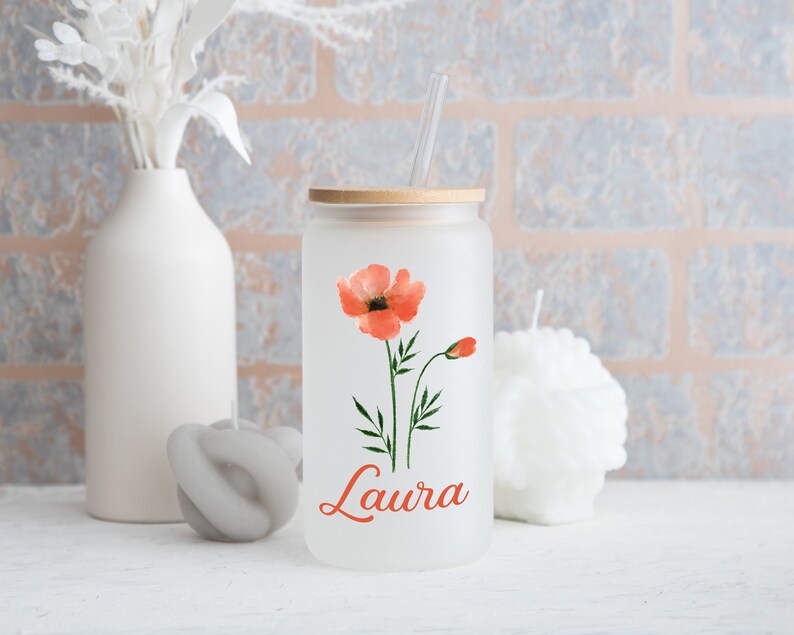 May include: A frosted glass tumbler with a bamboo lid and a clear straw. The tumbler features a watercolour poppy design in shades of orange and green, with the name "Laura" in orange script. The tumbler is part of a drinkware collection.