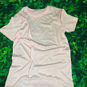 Op de afbeelding: Een effen, lichtroze T-shirt met korte mouwen en een ronde hals.