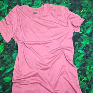 Op de afbeelding: Een effen, lichtroze T-shirt met korte mouwen en een ronde hals.