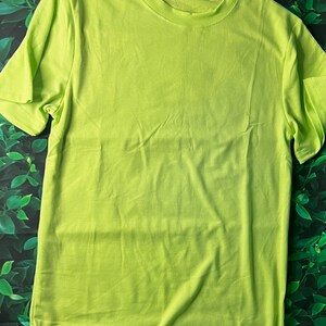 Puede incluir: Una camiseta de manga corta de color verde brillante hecha de una tela suave y c&oacute;moda. La camiseta es lisa y tiene cuello redondo.