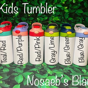 Op de afbeelding: Zes lege roestvrijstalen kinderbekers met verschillende gekleurde deksels en labels. De labels luiden: Teal/Red, Red/Purple, Red/Pink, Grey/Lime, Blue/Green en Blue/Grey. De bekers zijn in een rij op een groene, bladerrijke achtergrond gerangschikt. De tekst "Kids Tumbler" staat bovenaan de afbeelding en "Nosaeb's Blanks" onderaan.
