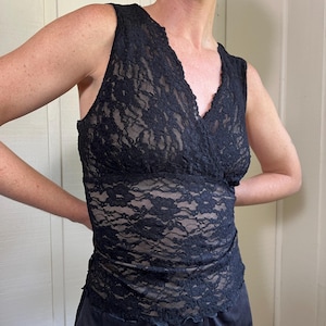 Puede incluir: Top de encaje negro con cuello en V. El top sin mangas presenta un estampado floral y una silueta ajustada. La parte inferior del top es de color negro liso. El top se combina con pantalones de satén negro.