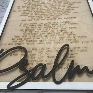 A rectangular white frame with the words from Psalm 91 laser etched onto the wood background. The words "Pslam91" is cut out in script letters and glued over the frame.