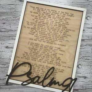 A rectangular white frame with the words from Psalm 91 laser etched onto the wood background. The words "Pslam91" is cut out in script letters and glued over the frame.
