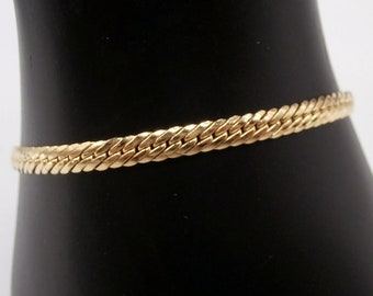 May include: A gold chain bracelet with a woven design.