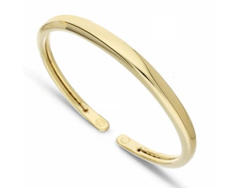 Puede incluir: Un brazalete simple de oro con un acabado liso y redondeado.