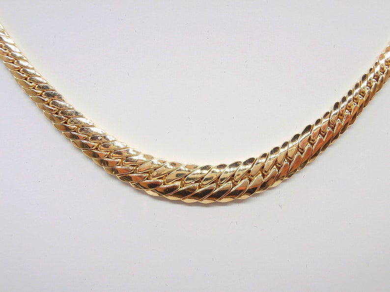 May include: A gold chain necklace with a thick, textured, interwoven design.