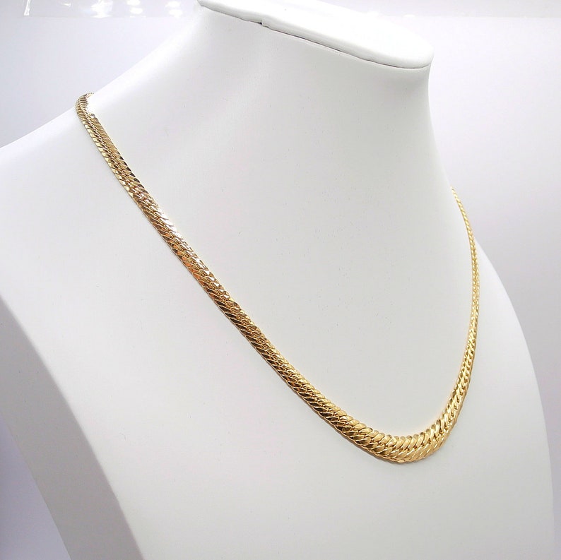 May include: A gold chain necklace with a snake chain design. The chain is on a white display stand.