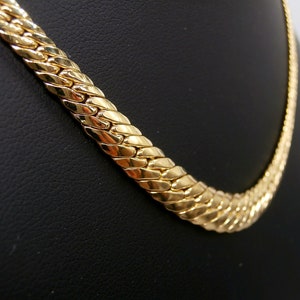 May include: A gold chain necklace with a thick, textured, snake-like design.