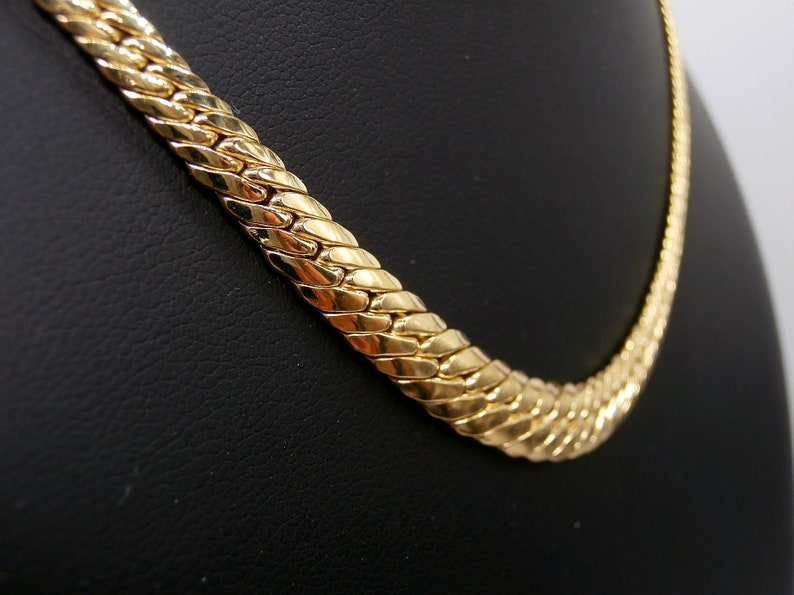 May include: A gold chain necklace with a thick, textured, snake-like design.