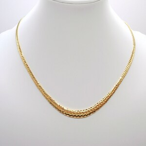 May include: A gold chain necklace with a textured, interwoven design. The chain is displayed on a white mannequin bust.