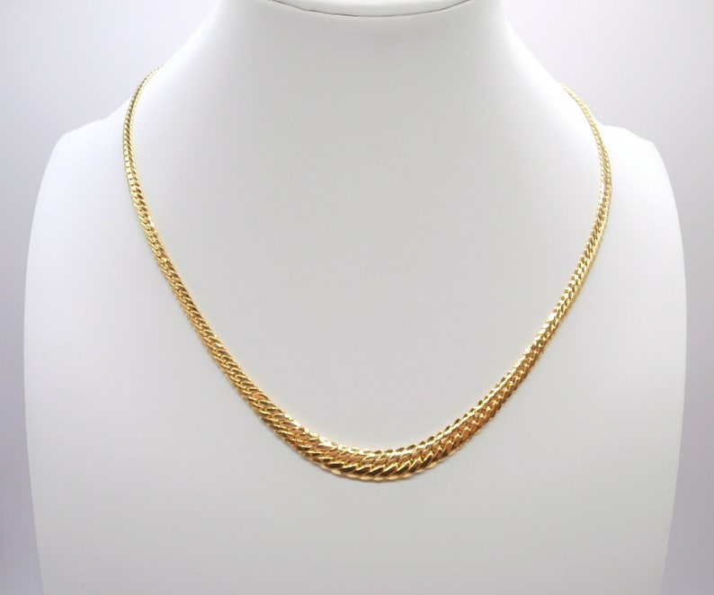 May include: A gold chain necklace with a textured, interwoven design. The chain is displayed on a white mannequin bust.