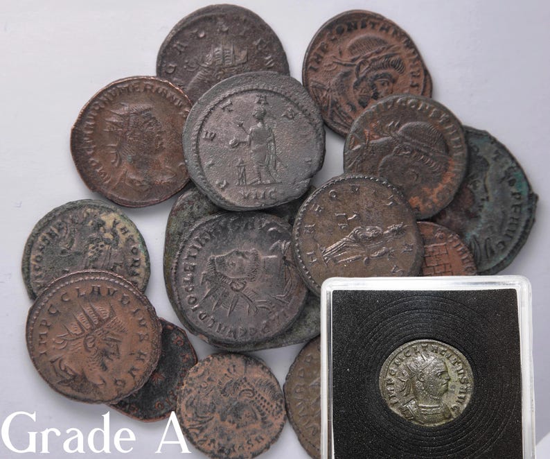 Peut inclure: Une collection de 12 pi&egrave;ces de monnaie en bronze romaines anciennes, certaines avec des inscriptions latines, dans diff&eacute;rents &eacute;tats de conservation. Les pi&egrave;ces sont dispos&eacute;es en pile sur une surface blanche. Une pi&egrave;ce est dans un &eacute;tui en plastique.