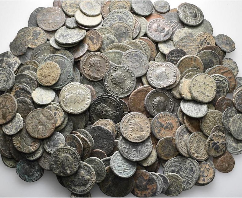 Peut inclure: Une grande collection de pi&egrave;ces de monnaie romaines anciennes, dont beaucoup pr&eacute;sentent des images visibles d'empereurs et d'autres personnages. Les pi&egrave;ces sont en bronze et ont un aspect us&eacute; et vieilli.