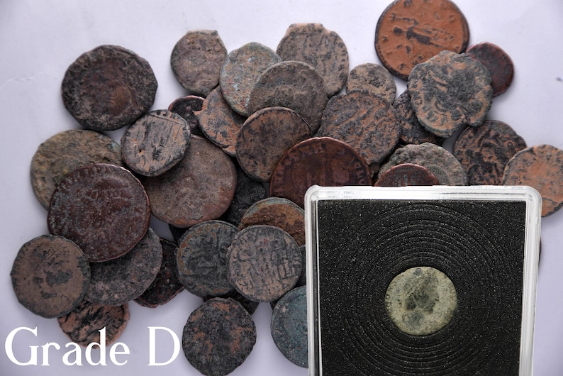 Peut inclure: Une collection de pi&egrave;ces de monnaie en cuivre romaines anciennes dans diff&eacute;rents &eacute;tats d'usure. Les pi&egrave;ces sont dispos&eacute;es en pile sur une surface blanche. Les pi&egrave;ces sont de tailles et de formes diff&eacute;rentes, et certaines portent des inscriptions visibles. Le texte "Grade D" est visible dans le coin inf&eacute;rieur gauche de l'image.