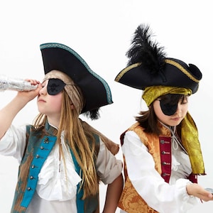 May include: Two children dressed as pirates, one looking through a telescope and the other holding a small treasure chest. Both are wearing eye patches and pirate hats.
