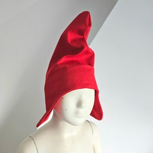 May include: A red felt gnome hat with a pointed top and a long, flowing brim.