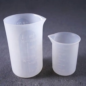 Peut inclure: Deux gobelets doseurs en silicone transparent, l'un d'une capacité de 250 ml et l'autre d'une capacité plus petite. Les deux gobelets sont gradués en millilitres.