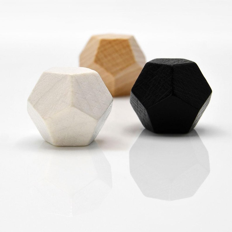Pu&ograve; includere: Tre forme geometriche in legno di colore bianco, nero e legno naturale. Ogni forma &egrave; un dodecaedro, una figura geometrica a 12 facce.