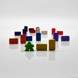 Può includere: Un pezzo da gioco verde a forma di stella si trova davanti a una fila di blocchi di legno colorati. I blocchi sono disposti a semicerchio e sono di varie tonalità di rosso, blu, giallo e viola.