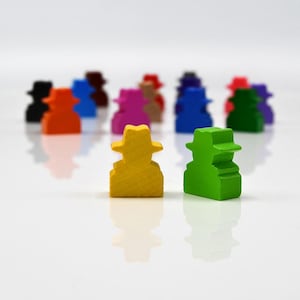 Op de afbeelding: Een verzameling kleurrijke houten spelstukken in de vorm van figuren met hoeden. De stukken zijn in verschillende kleuren, waaronder geel, groen, oranje, blauw en roze. De figuren zijn gerangschikt op een wit oppervlak.