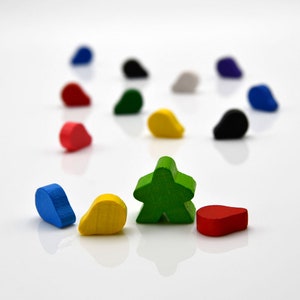 May include: A green five-pointed star shaped game piece surrounded by 10 smaller teardrop shaped game pieces in various colors, including blue, red, yellow, and black.