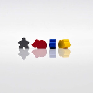 Può includere: Quattro pezzi di gioco in legno in fila su una superficie bianca. I pezzi sono una forma di persona grigia, una forma di topo rosso, un quadrato blu e un cerchio giallo.