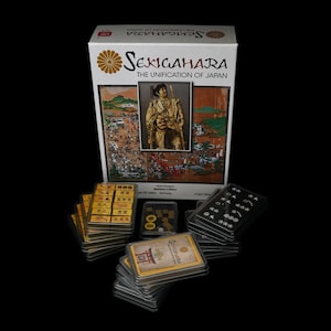 Può includere: Una scatola di gioco da tavolo con un'illustrazione in stile giapponese di un guerriero samurai sul davanti. La scatola è intitolata "Sekigahara: The Unification of Japan".
