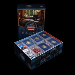 Può includere: Una scatola blu con un tabellone da gioco all'interno. La scatola ha un'immagine di una donna seduta a una scrivania con un globo. Il testo sulla scatola dice "Mr. President: The American Presidency 2001-2021".