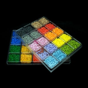 Pode incluir: Uma bandeja de plástico transparente cheia de pequenas contas coloridas. As contas estão organizadas em filas e colunas, com cada fila contendo uma cor diferente. As cores incluem vermelho, laranja, amarelo, verde, azul, roxo, rosa e marrom.