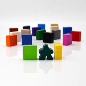 Puede incluir: Una colección de bloques de madera de colores en varias formas y tamaños, incluyendo cuadrados, rectángulos y un bloque en forma de estrella. Los bloques están dispuestos en un semicírculo sobre una superficie blanca.